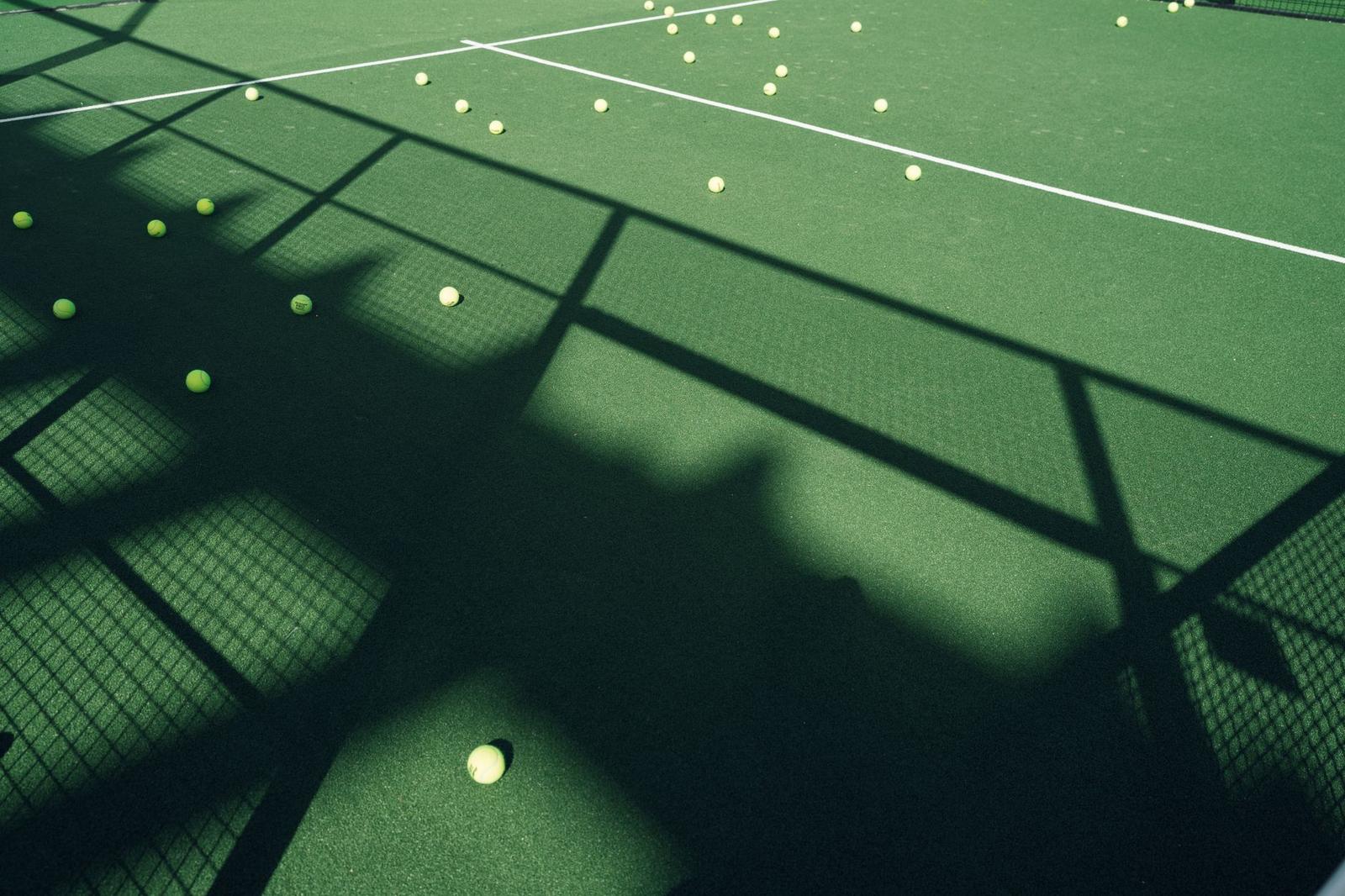 Scattered Tennis Balls on Court with Shadow Play